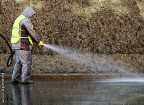 Worker in overalls pouring asphalt pavement water from the rubber was. © Ilia Shcherbakov