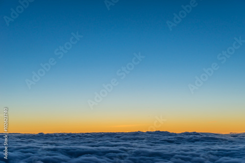 a view form passanger plane's window on the sun setting above the cloud level.