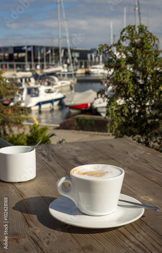 Hot coffee on wood table with blur port background