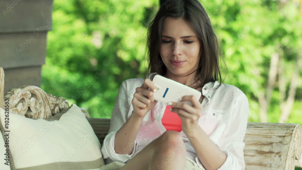 Young woman playing game on smartphone while sitting on wooden sofa on terrace
Young woman playing game on smartphone while sitting on wooden sofa on terrace