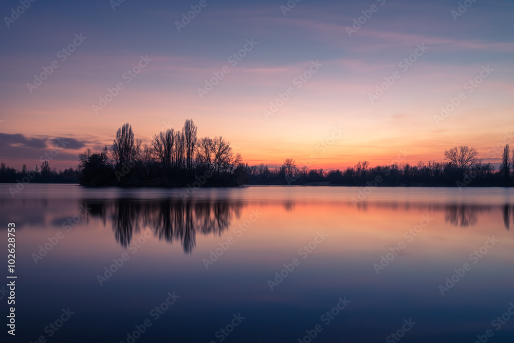 Farbiger Sonnenuntergang mit Wasserspiegelungen  am See