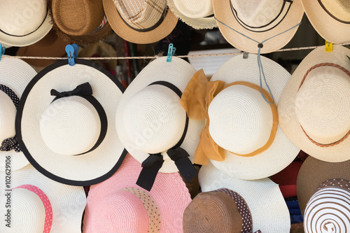 Straw hats for sale, hanging on a wall..