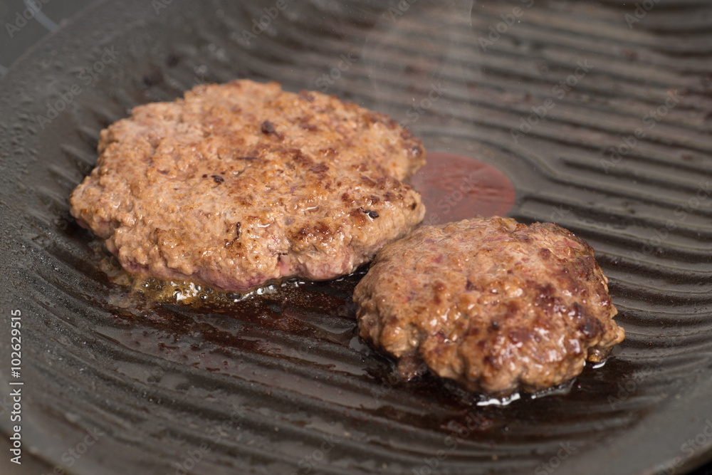 Fresh meat cutlets in a frying pan grill