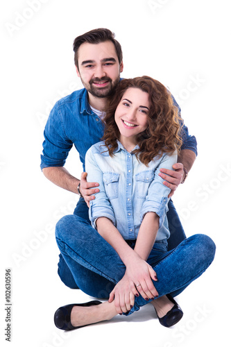 happy couple sitting on the floor isolated on white