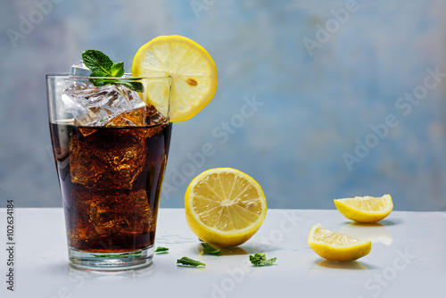 glass of cola or coke with ice cubes, lemon slice and peppermint photo