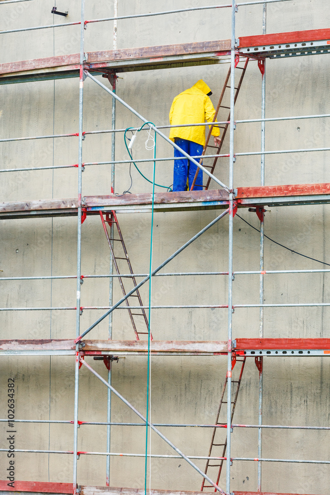 Man cleaning wall. Scaffolding