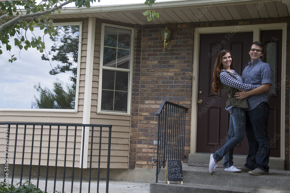 new home owners on front door steps of new home