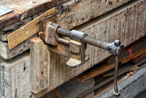 Adjustable clamp tool equipped at a vintage carpenter's work bench.