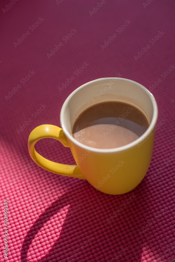 Gourmet Hot Chocolate Milk in yellow cup on pink yoga mat with w Gourmet Hot Chocolate Milk in yellow cup on pink yoga mat with w