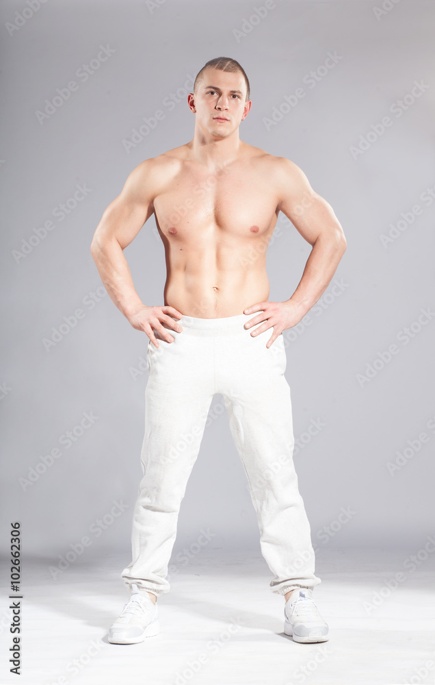 young sporty muscular man ready to workout on gray background young sporty muscular man ready to workout on gray background