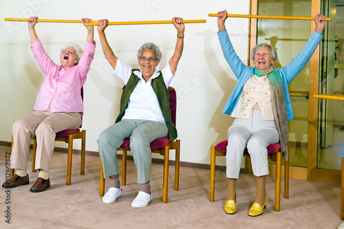 Three happy elderly ladies doing exercises.