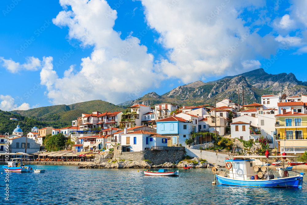 Fishing boats in Kokkari port with colourful Greek houses in background, Samos island, Greece