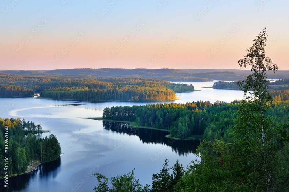 Naklejka premium Clear blue Saimaa lake at sunset, Finland, aerial view. Picturesque panoramic scenery. Atmospheric landscape. Pure nature, ecology, environmental conservation, eco tourism, travel destinations