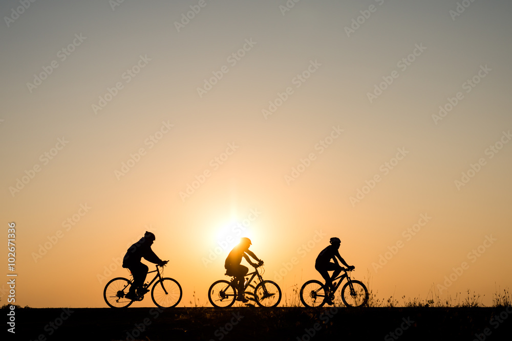 Silhouette of cyclist with friend motion on sunset background Silhouette of cyclist with friend motion on sunset background