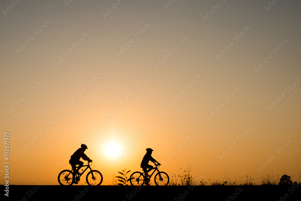 Silhouette of cyclist with friend motion on sunset background Silhouette of cyclist with friend motion on sunset background