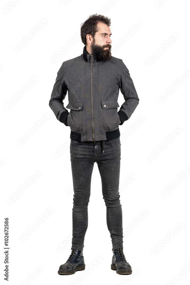 Serious bearded punker in gray jacket, tight jeans and old army boots looking away. Full body length portrait isolated over white studio background. Serious bearded punker in gray jacket, tight jeans and old army boots looking away. Full body length portrait isolated over white studio background.