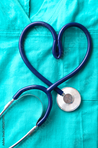A stethoscope shaping a heart and a clipboard on a medical uniform, closeup