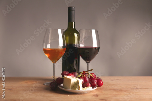 Refined still life of wine, cheese and grapes on wicker tray on wooden table
