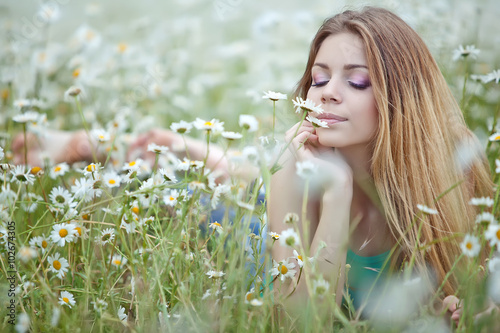 Beautiful young woman in a camomile field 