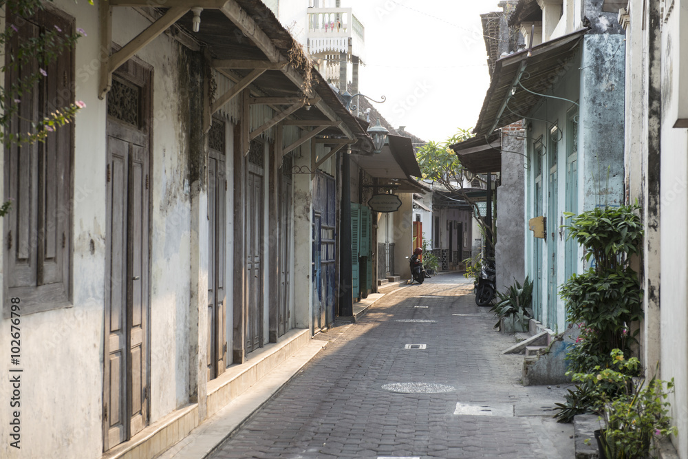 Calle estrechas de la ciudad de Surakarta con hombre empujando una carreta, Java Indonesia