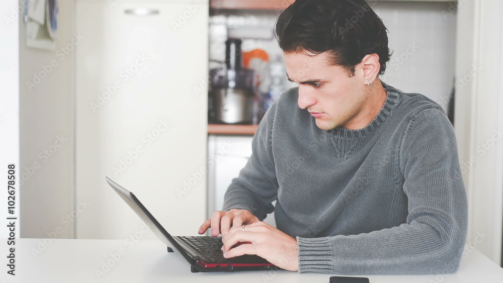 Young handsome caucasian brown hair man sitting at the table tapping on the keyboard of a notebook – business, communication, social network concept Young handsome caucasian brown hair man sitting at the table tapping on the keyboard of a notebook – business, communication, social network concept