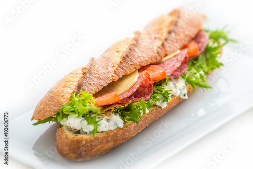 long sandwich with ham, cheese, tomatoes and lettuce. Isolated on white background