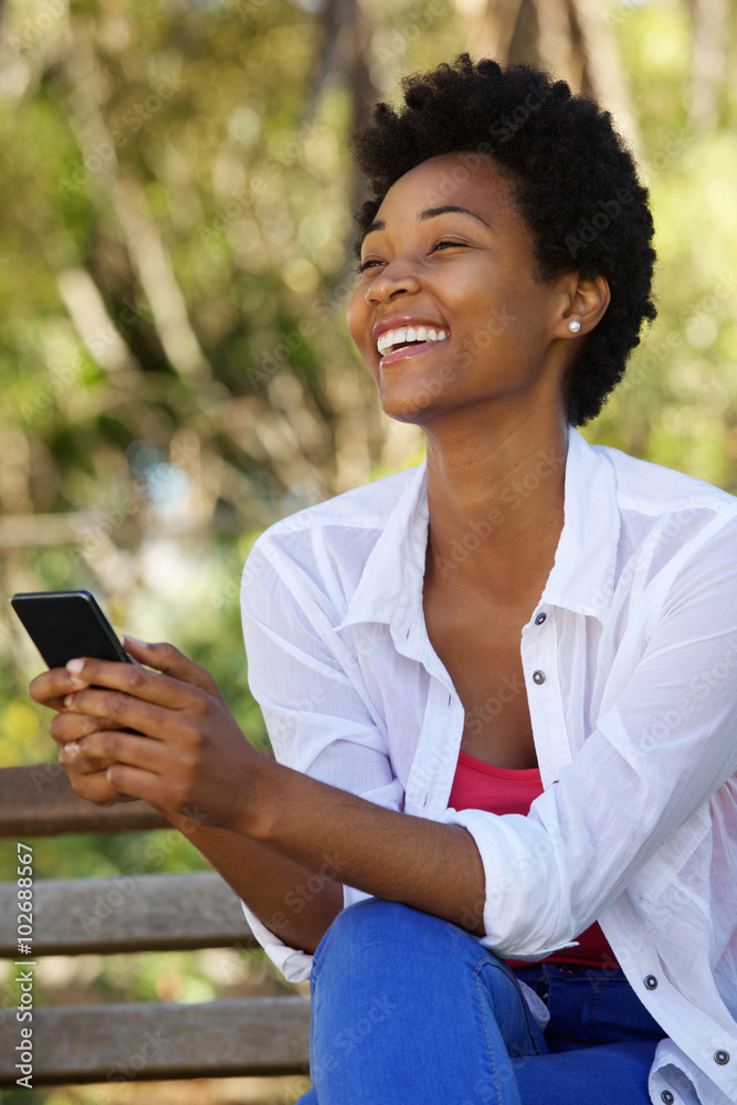Cheerful young woman sitting on a bench with a mobile phone Cheerful young woman sitting on a bench with a mobile phone