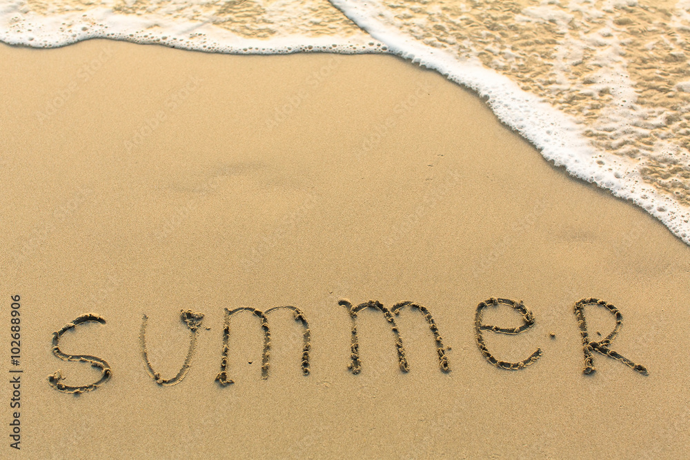 Summer - word drawn on the sand beach with the soft wave.