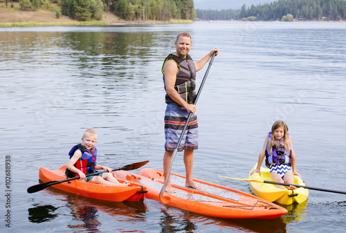 Attractive family kayaking and paddle boarding together on a beautiful lake