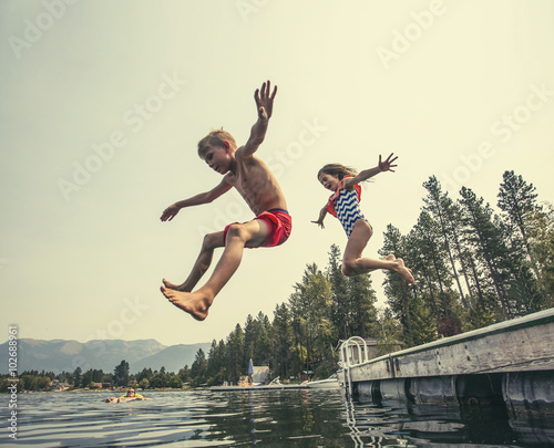 Photo Kids jumping off the dock into a beautiful mountain lake