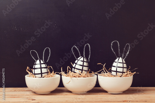 Modern easter egg decorations with bunny ears on chalkboard. Creative easter background.