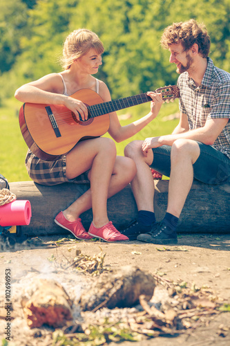 Young couple camping playing guitar outdoor