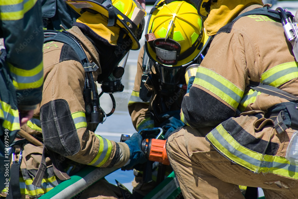 Naklejka premium Firefighters training for fire with water hose