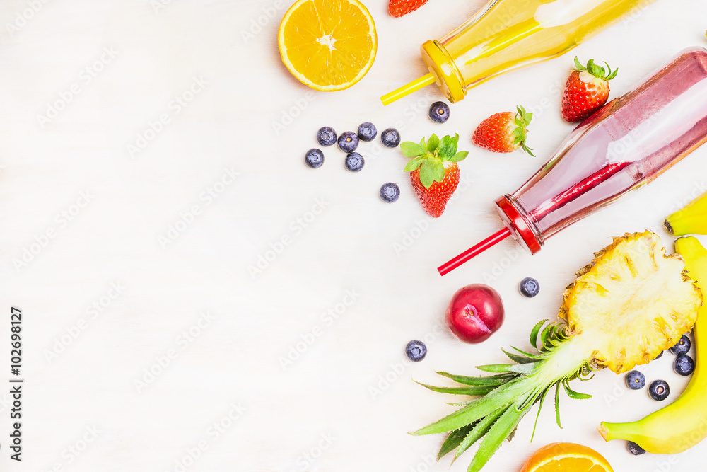 Red and yellow smoothies in bottles with fruits ingredients on white wooden background, top view, place for text. Superfoods and healthy lifestyle or detox diet food concept. Red and yellow smoothies in bottles with fruits ingredients on white wooden background, top view, place for text. Superfoods and healthy lifestyle or detox diet food concept.