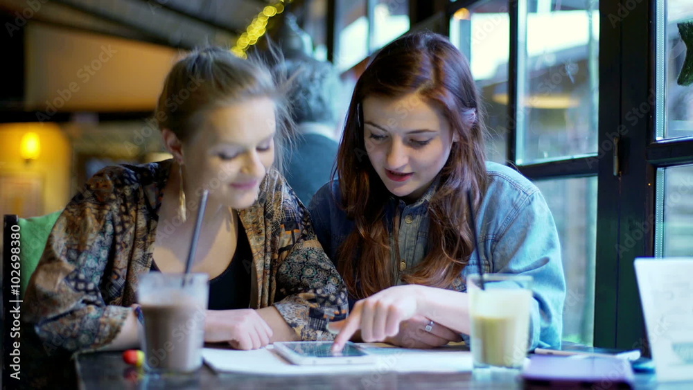 Girls browsing internet on tablet and smiling to the camera in the cafe
Girls browsing internet on tablet and smiling to the camera in the cafe