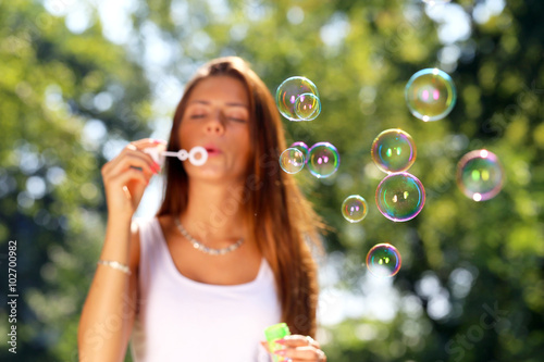 young girl blowing soap bubbles in park