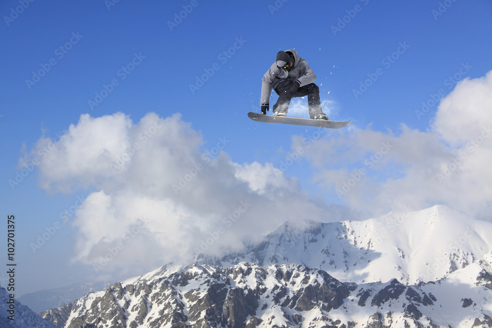 Flying snowboarder on mountains. Extreme sport.