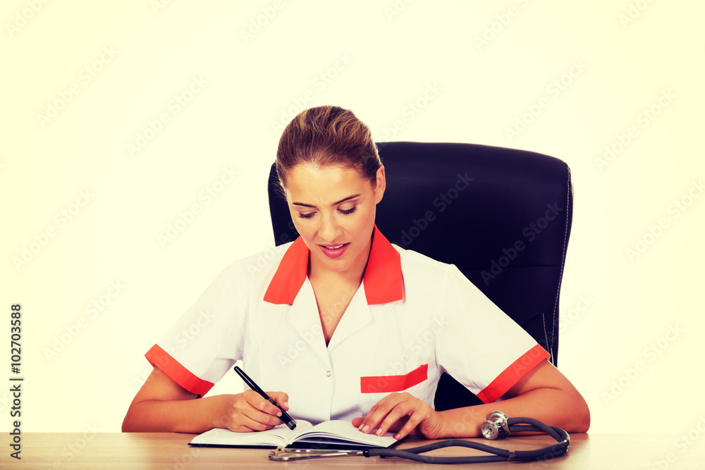 Doctor sitting behind the desk and writing a notes Doctor sitting behind the desk and writing a notes