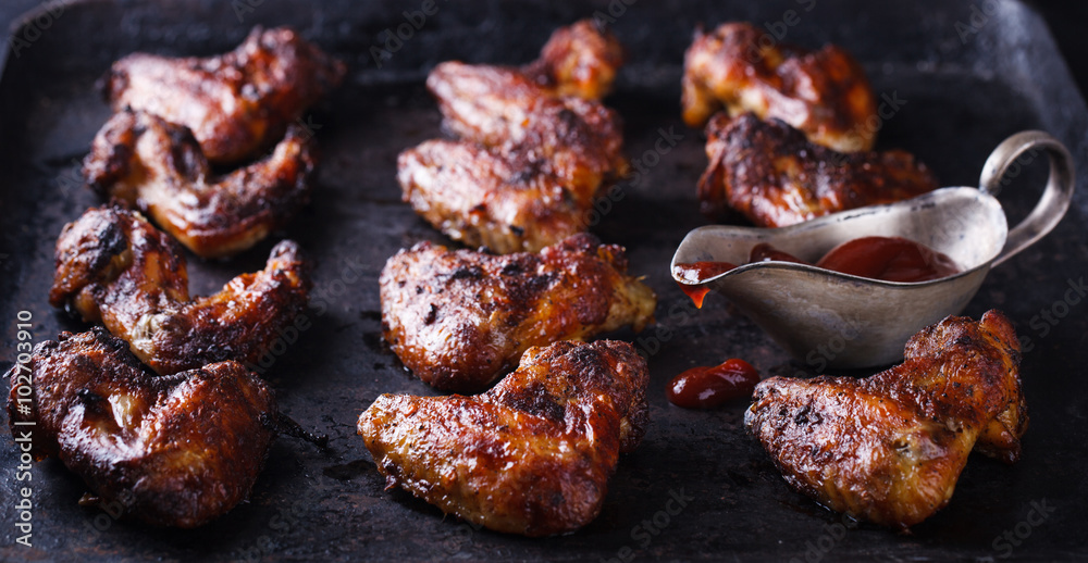 Chicken wings fried on the grill with BBQ sauce on a dark background.selective focus. Chicken wings fried on the grill with BBQ sauce on a dark background.selective focus.