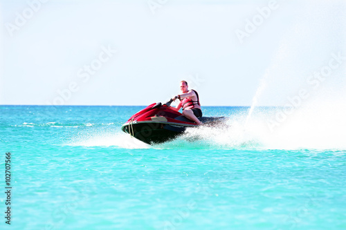 Fotografija Young guy cruising on a jet ski on the caribbean sea