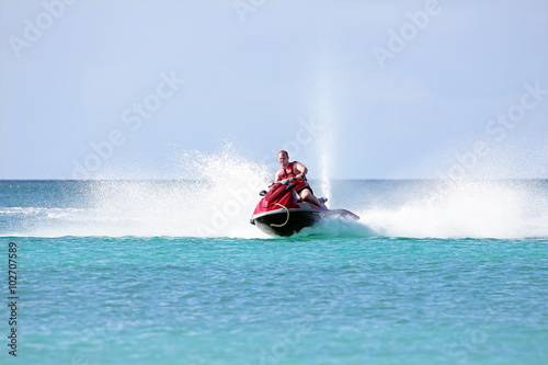 Obraz na plátně Young guy cruising on a jet ski on the caribbean sea