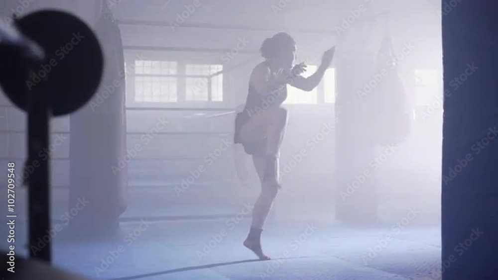 Female muay thai boxer shadowboxing in a boxing club with a ring at background. Dolly move. UHD, 4K. Female muay thai boxer shadowboxing in a boxing club with a ring at background. Dolly move. UHD, 4K.