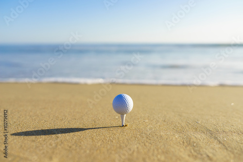 Golf Ball on a tee at a California beach with white wave in Pacific Ocean