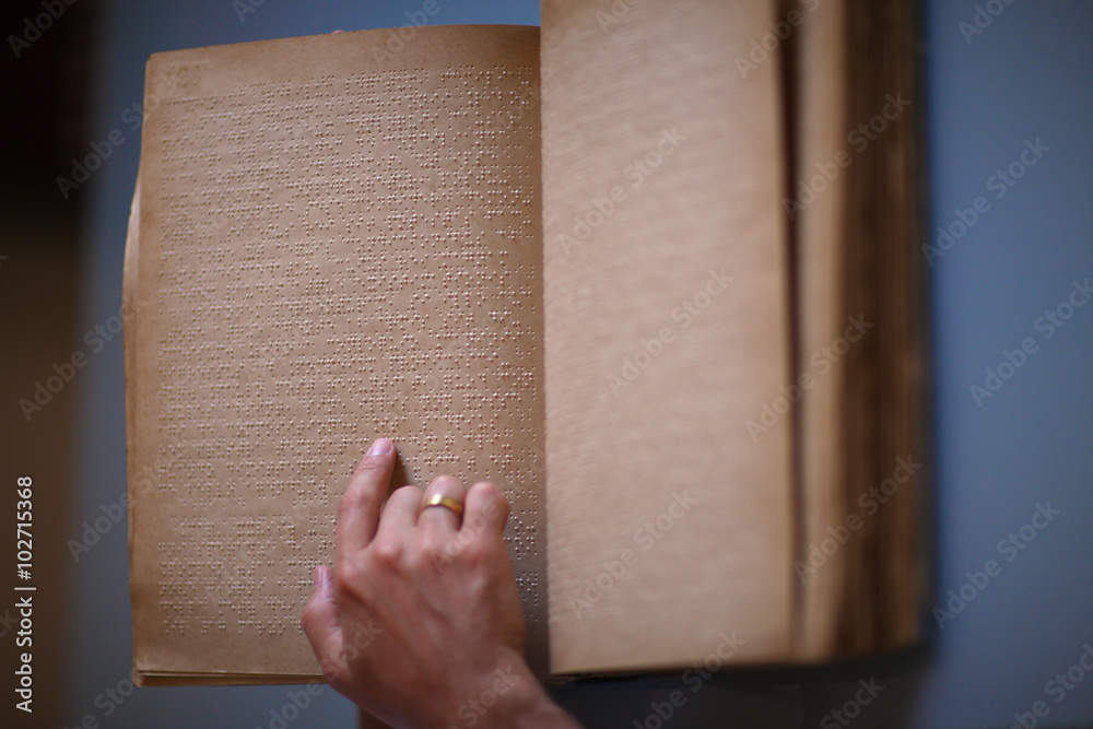 Raised dots read by a finger of a blind person Raised dots read by a finger of a blind person