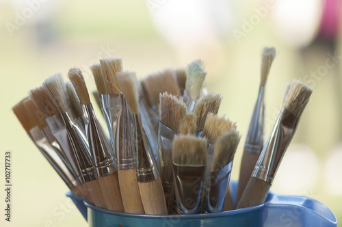 Painting brushes in a plastic recipient near a window