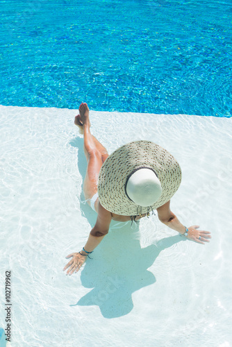 woman wearing a big hat relaxing at the swimming pool