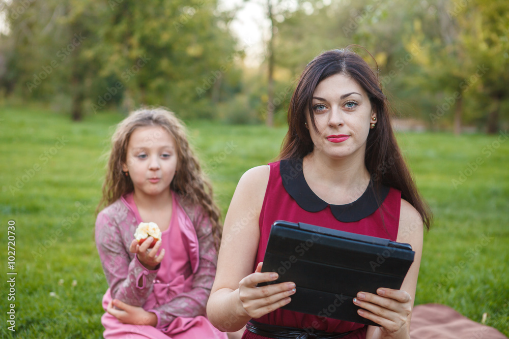 Mom and daughter in the park using tablet computer Mom and daughter in the park using tablet computer