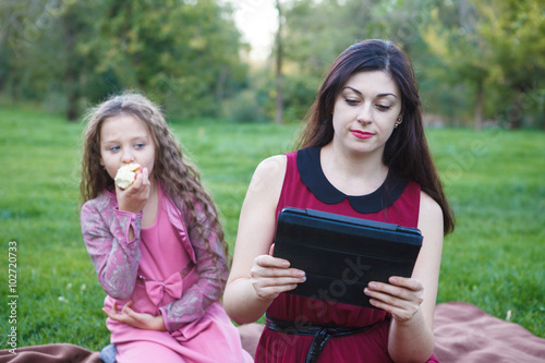 Mom and daughter in the park using tablet computer