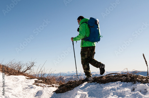 Male backpacker walking on mountain peak.