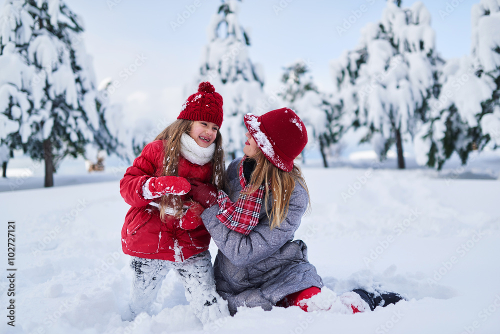 daughter with mother play in snow-covered park